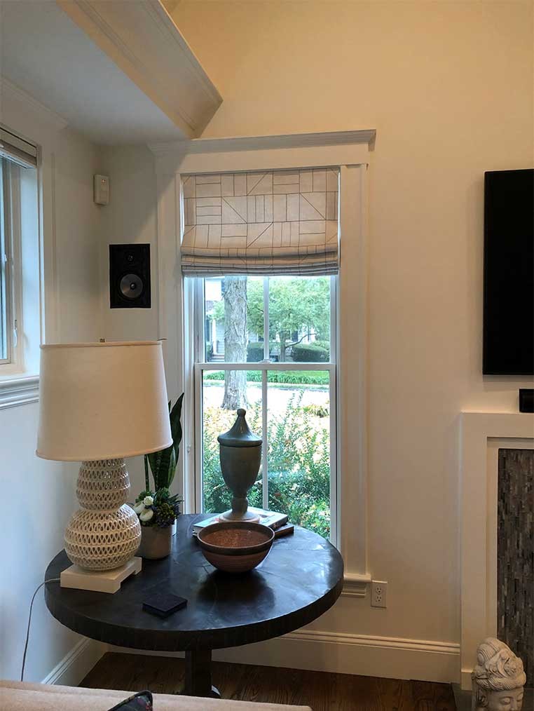 A round table with lamp next to a tall window